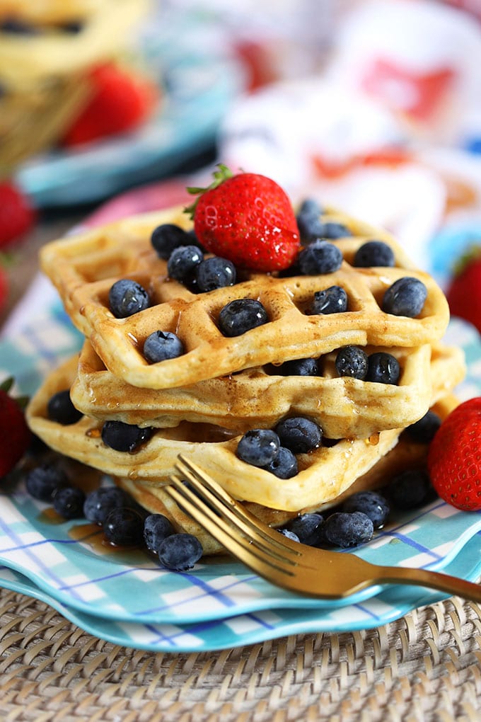 Stack of waffles on a blue plaid plate with berries and a gold fork from TheSuburbanSoapbox.com