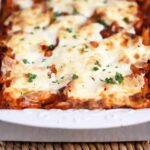 The BEST Baked Ziti in a white casserole on a wicker placemat from TheSuburbansoapbox.com