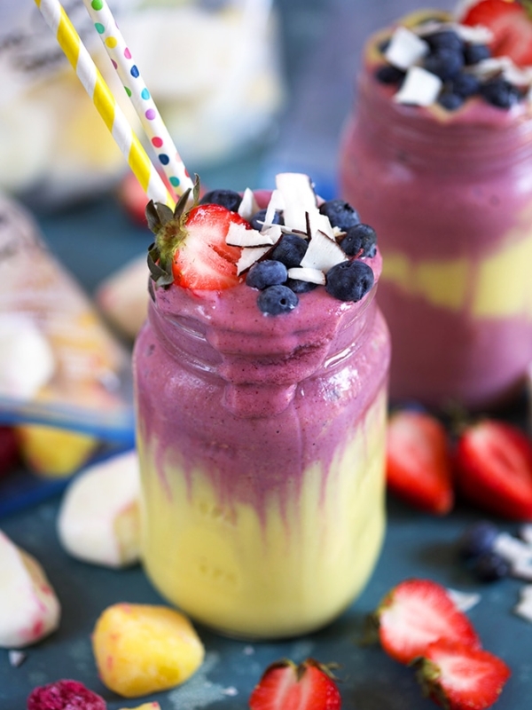 Layered smoothie recipe with fruit on a blue background from TheSuburbansoapbox.com