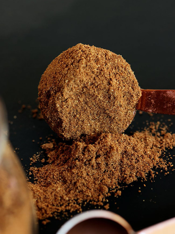 Pumpkin Pie spice in a copper measuring spoon on a black background.