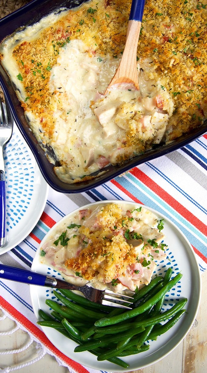 Overhead shot of Chicken Cordon Bleu Casserole in a navy baking dish and a serving on a plate with green beans.