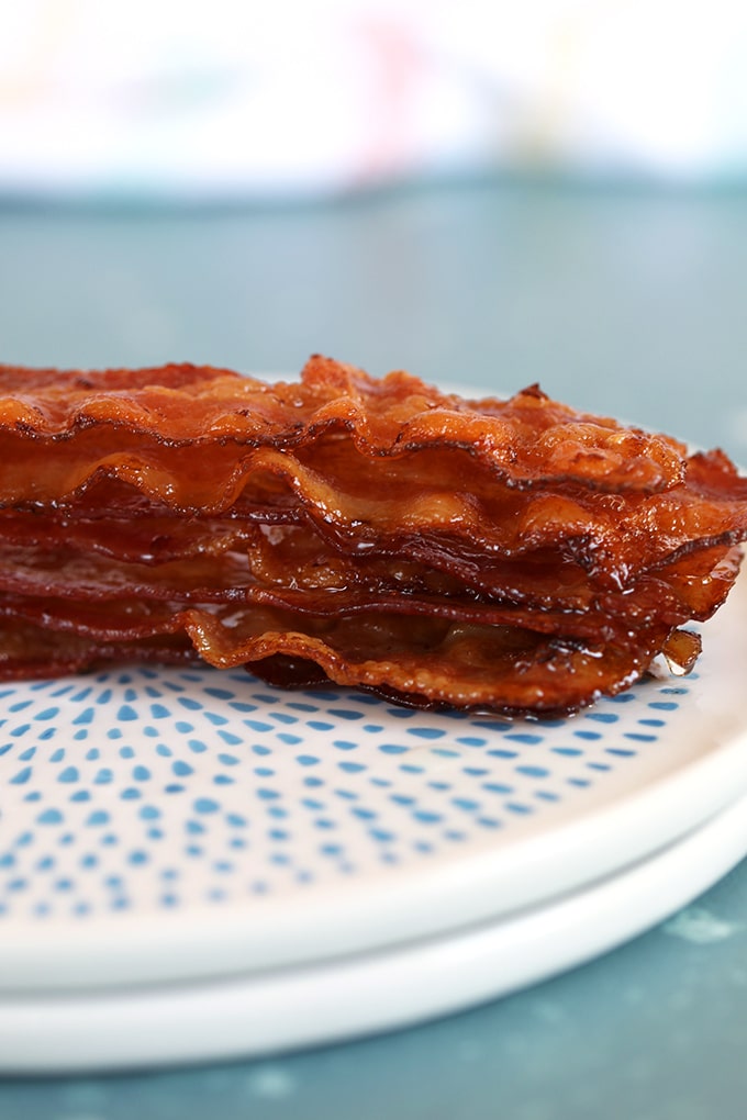 Close up shot of stacked bacon on a white plate with blue dots.