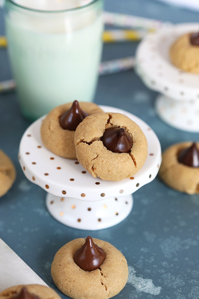 Peanut butter blossom cookies on a cupcake stand with a glass of milk in the background.