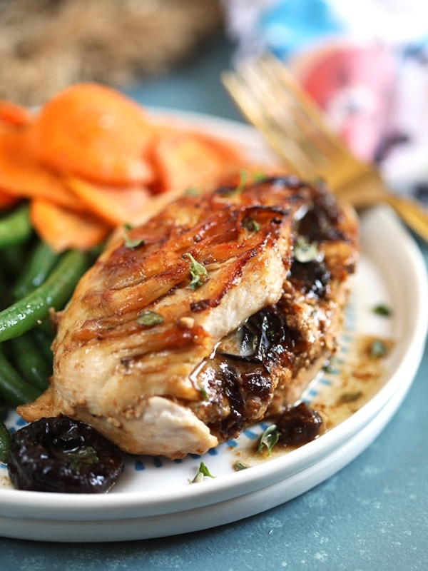 Close up shot of goat cheese stuffed chicken breast on a white plate.