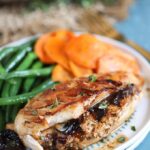 Prune Goat Cheese Stuffed Chicken on a white plate with green beans and carrots.
