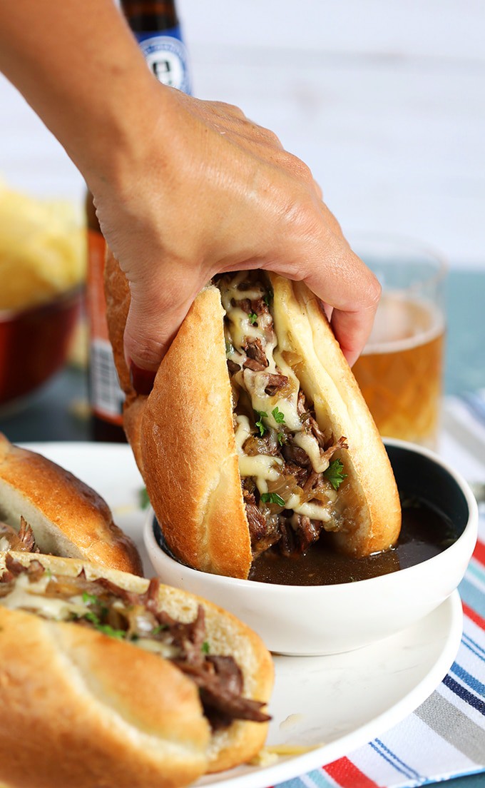 French Dip Sandwich being dipped into au jus.