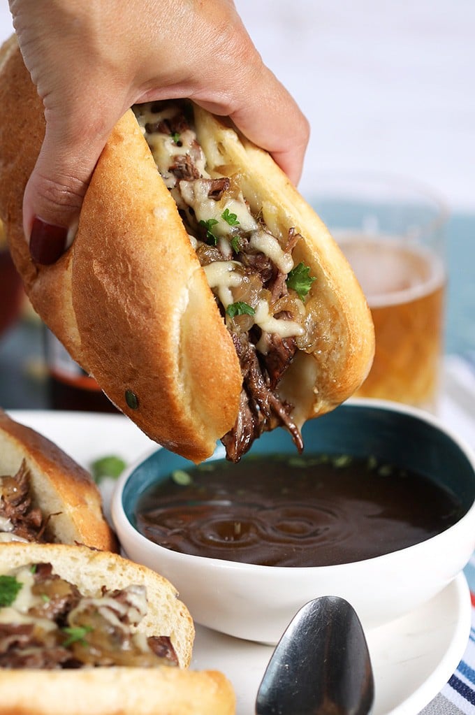 French Dip sandwich close up shot of being dipped into au jus.