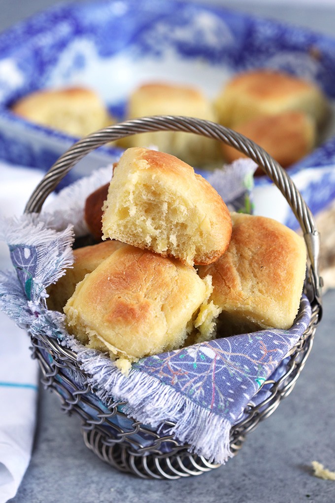 Dinner rolls in a basket with blue linens.
