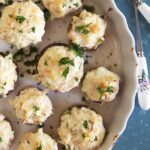 Crab Stuffed Mushrooms in a baking dish with lemons on a blue background.
