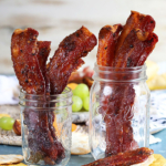 Sweet and spicy candied bacon in two mason jars.