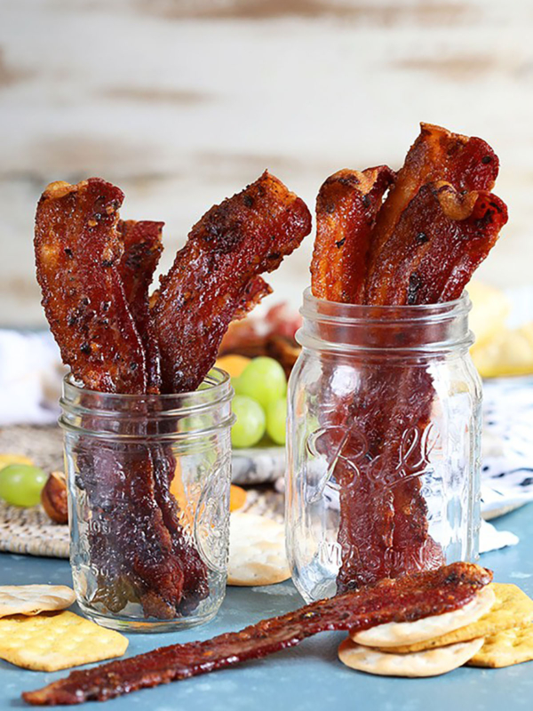 Sweet and spicy candied bacon in two mason jars.