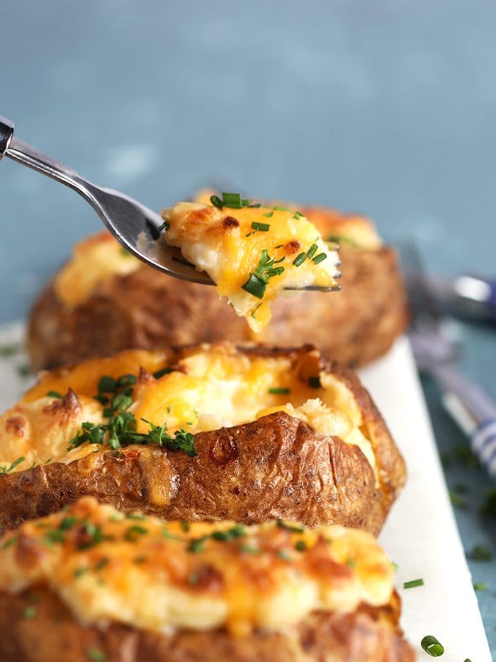 Close up of twice baked potatoes with a fork taking a bite.
