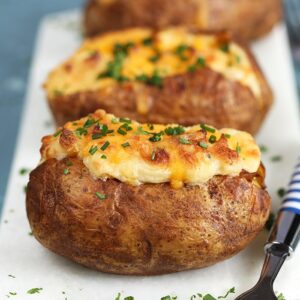 Twice Baked Potatoes with Cheddar and Chives on a white marble board.