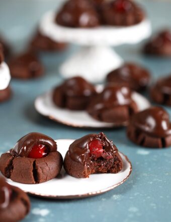 Chocolate Covered Cherry Cookies with a bite taken out on a white plate.