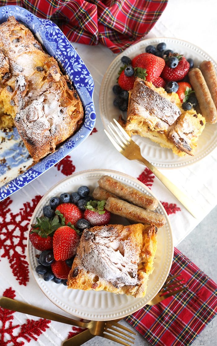 Slice of Panettone French Toast Casserole on a white plate with sausage and berries.