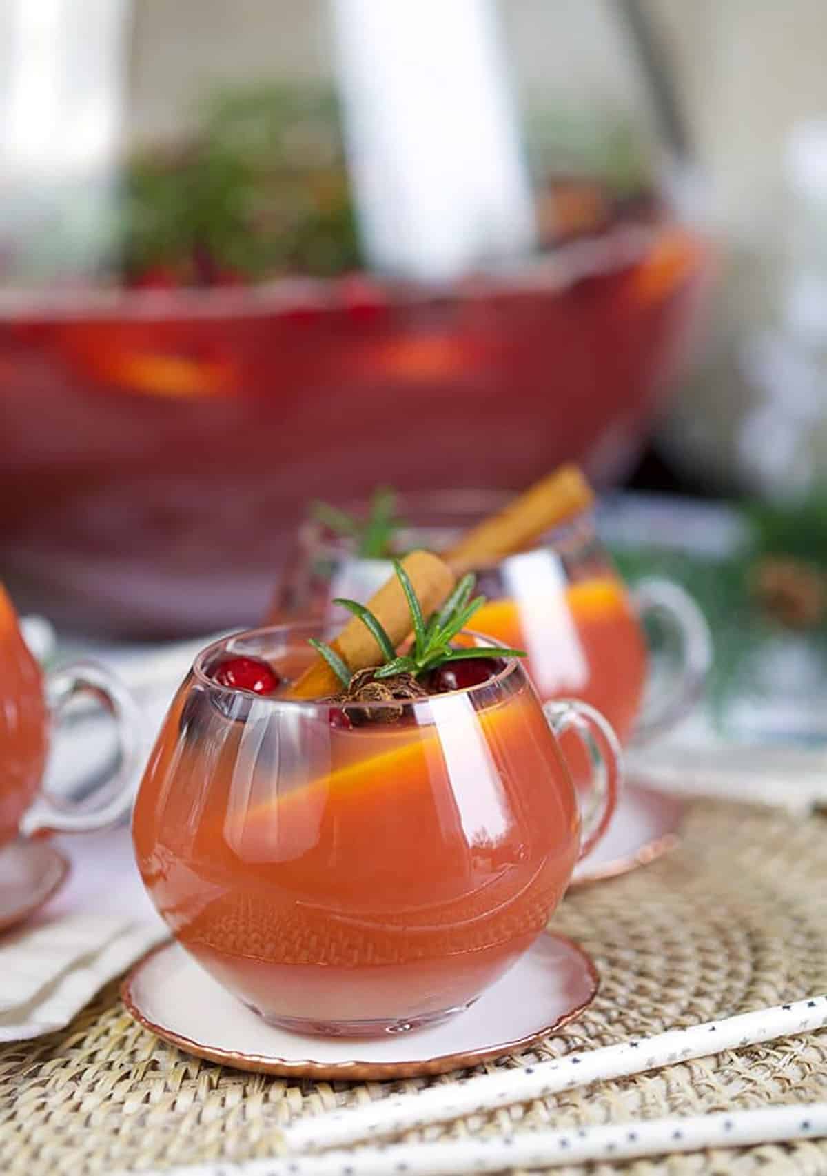 Glass of sparkling pomegranate rum punch with cinnamon sticks, rosemary and cranberry.