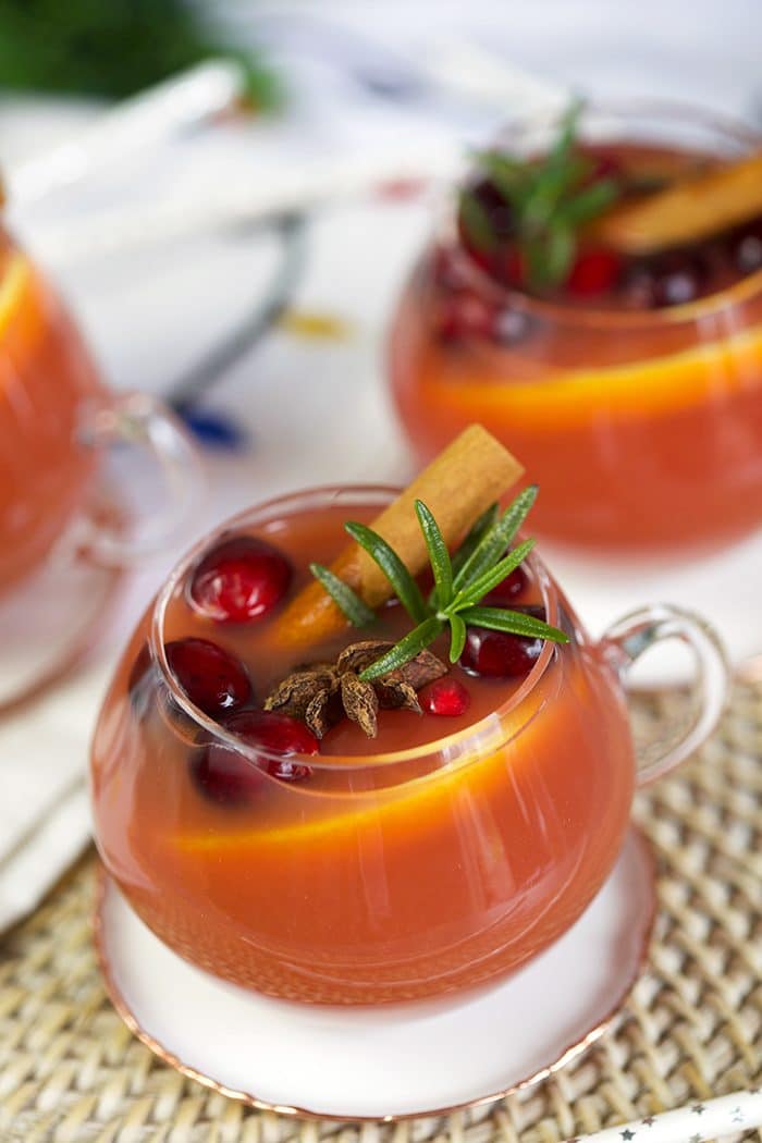 Close up shot of sparkling pomegranate rum punch in a glass with cinnamon stick and rosemary.