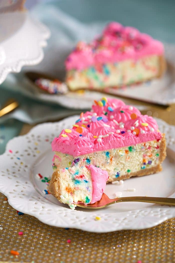 Funfetti Cheesecake recipe with a fork on a plate with a bite ready to eat.