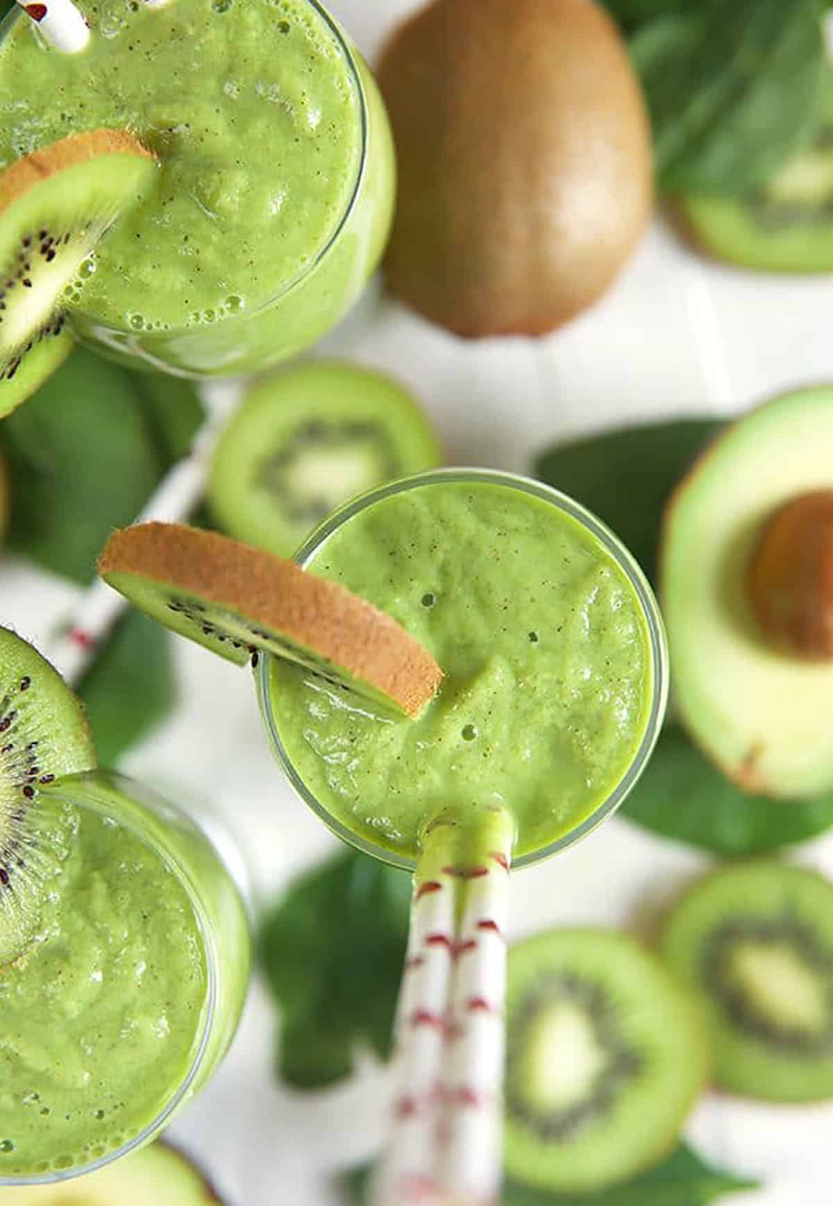 Overhead shot of Kiwi Pineapple Spinach Smoothie with avocado half and kiwi slices.