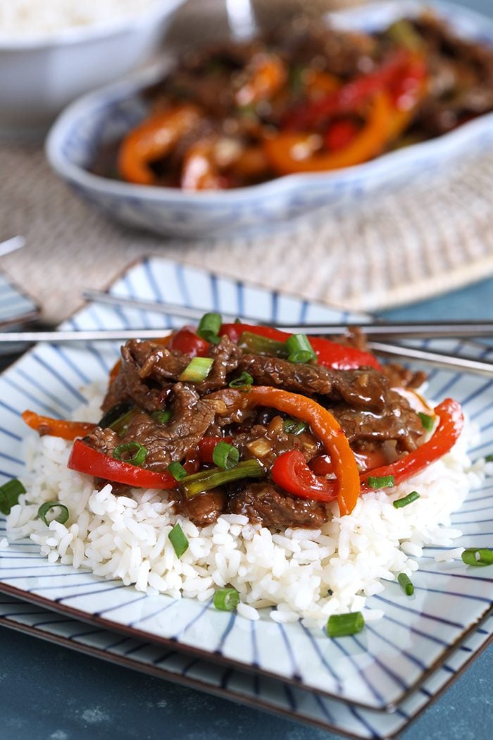 Mongolian Beef Stir Fry on a bed of white rice on a blue and white square plate.