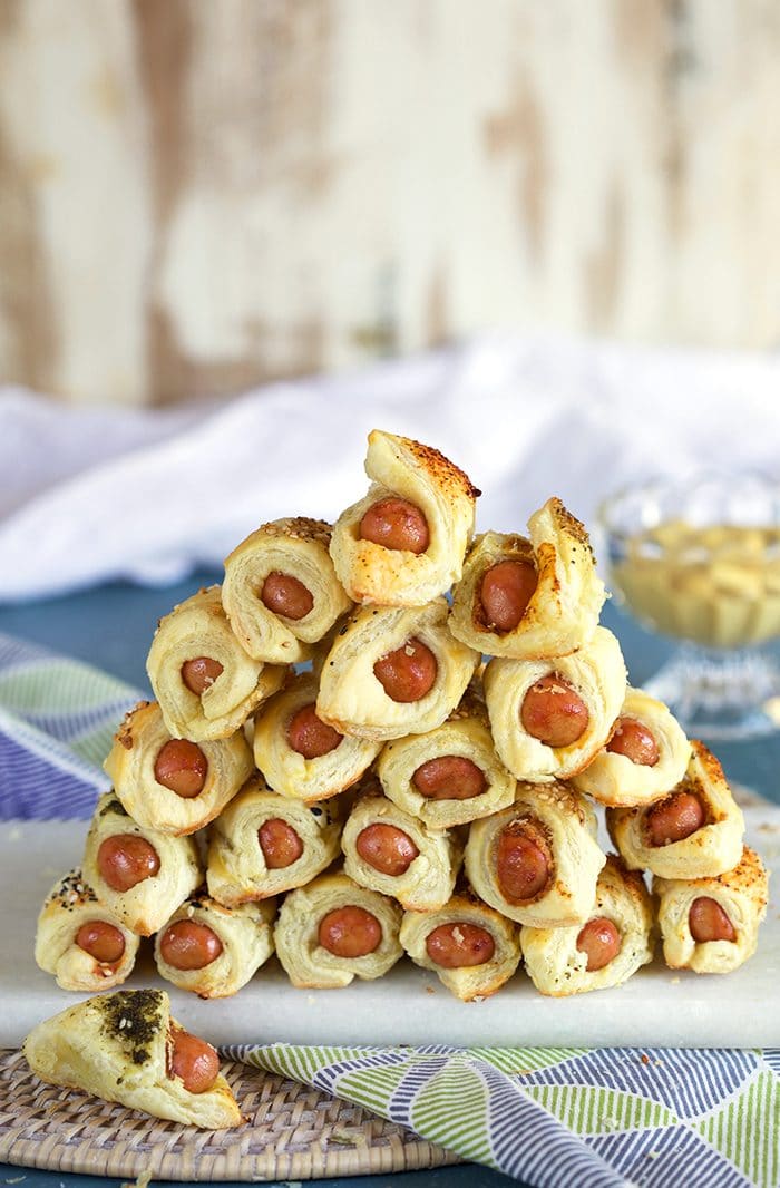Pigs in a blanket piled in a pyrimad form on a marble tray.