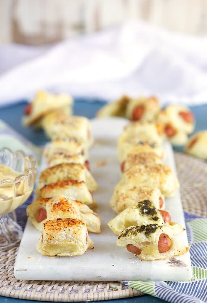 Pigs in a Blanket arranged in two rows on a white marble board.