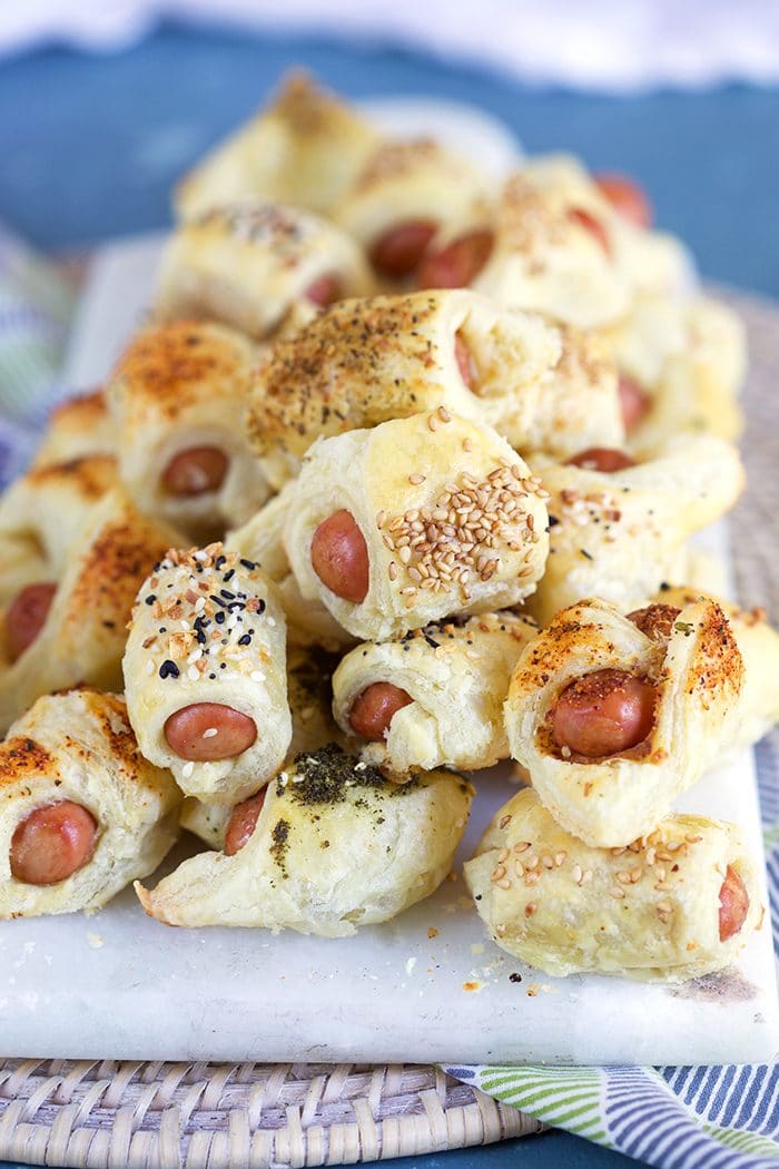Pile of pigs in a blanket with seasonings on a marble tray.
