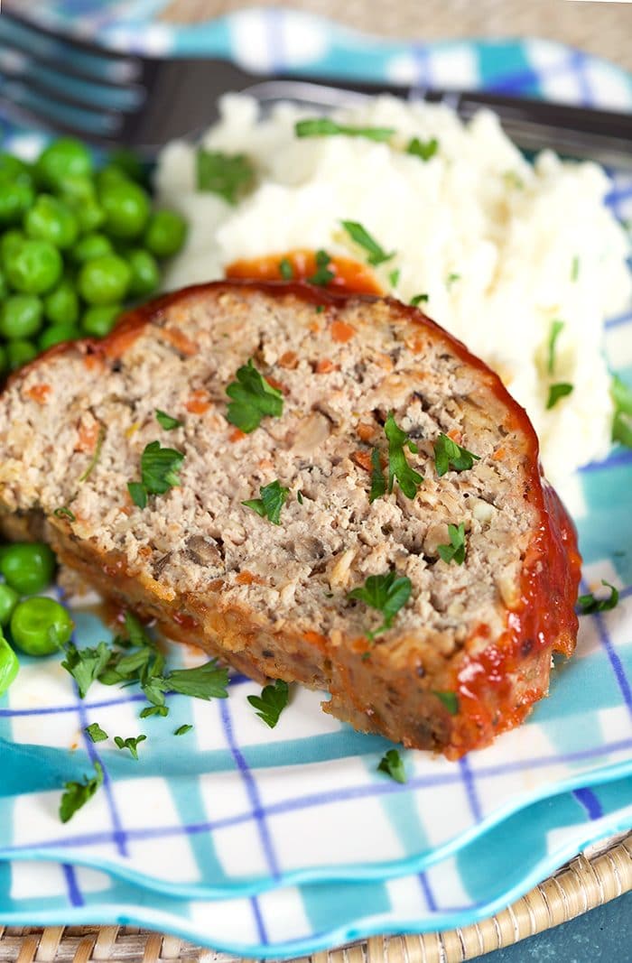 Close up shot of Turkey meatloaf on a plaid plate with mashed potatoes.