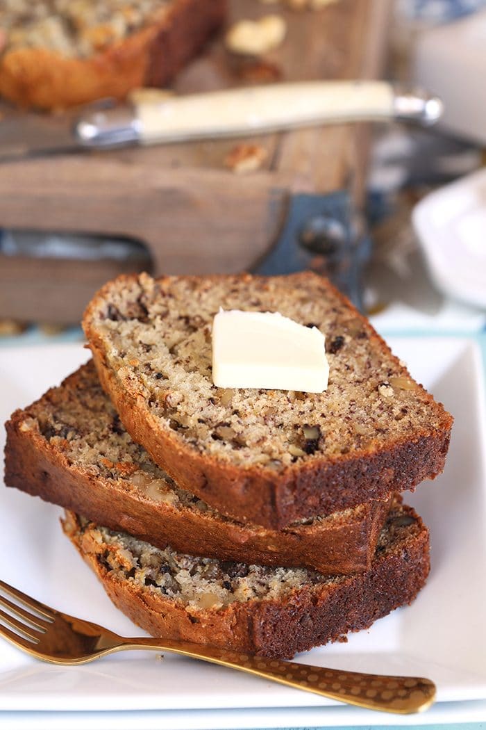 Three slices of Banana Nut Bread stacked on a white square plate.