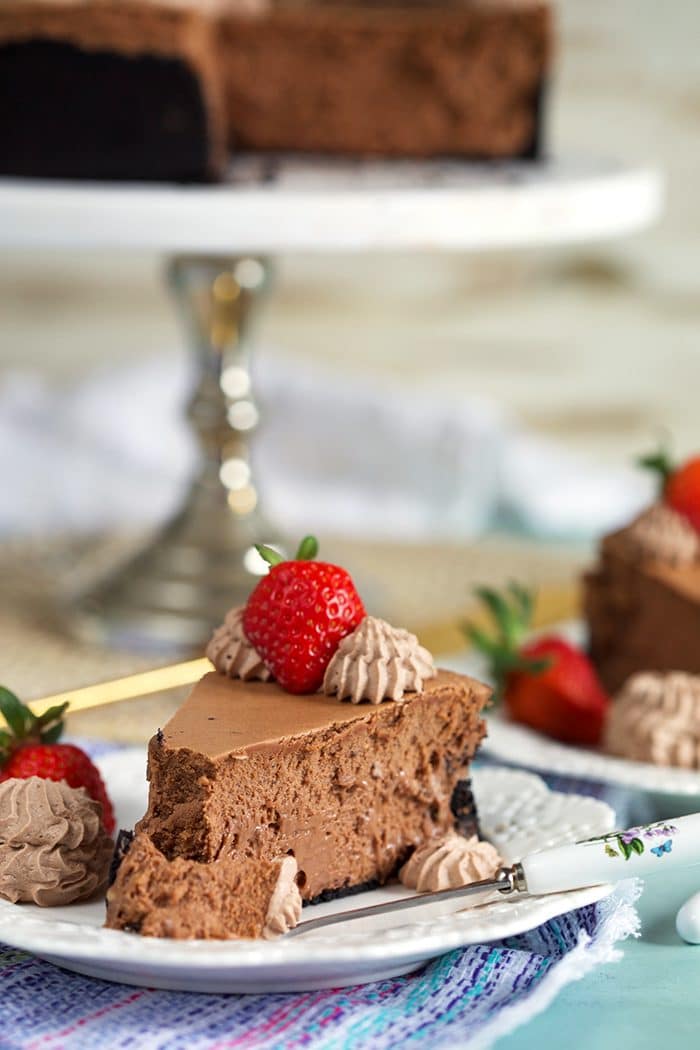 Slice of Chocolate Cheesecake on a white plate with a strawberry on top.