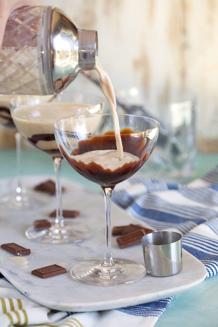 Chocolate Martini being poured into a martini glass with chocolate sauce swirled in the glass.