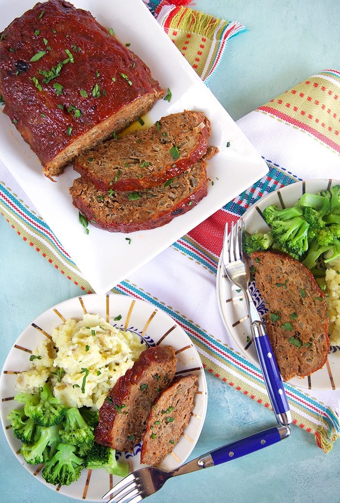 Overhead shot of dinner table set with crockpot meatloaf on a rectangle white platter.