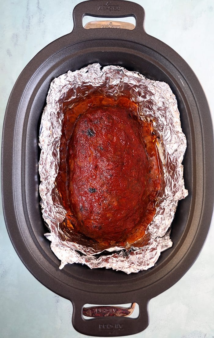 overhead shot of crockpot meatloaf in a slow cooker with foil