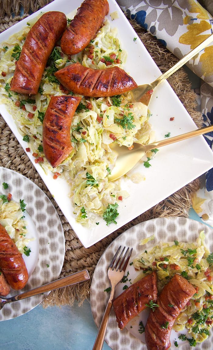 Overhead shot of fried cabbage and kielbasa on a white platter.