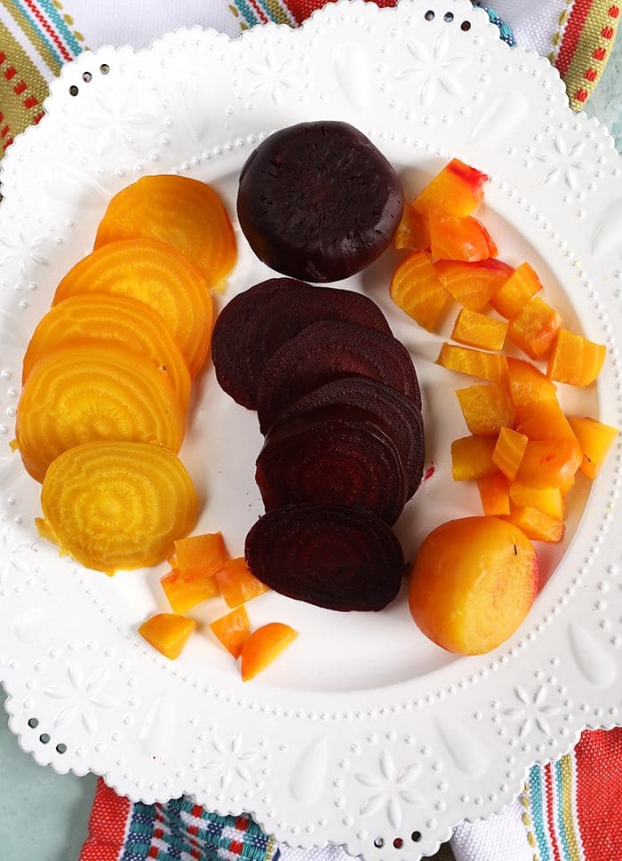 overhead shot of golden and red cooked beets on a white plate.