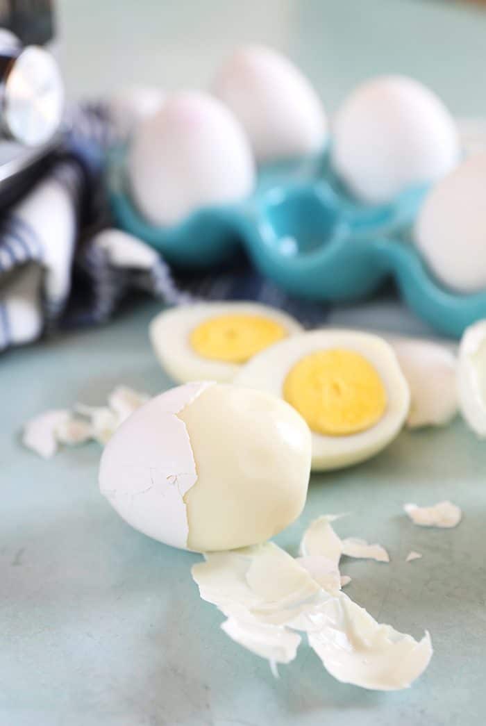 Perfectly peeled hard boiled egg on a blue background with a hard boiled egg cut in half.