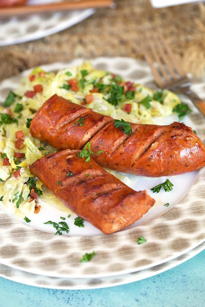 Fried Kielbasa with cabbage on a white plate.