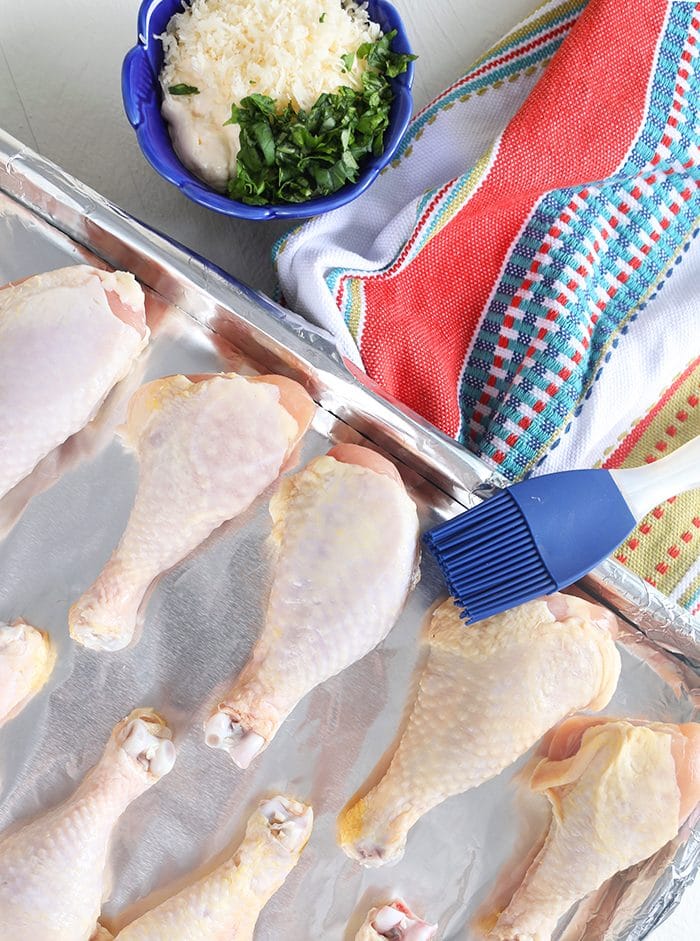 Raw chicken drumsticks on a baking sheet lined with foil.
