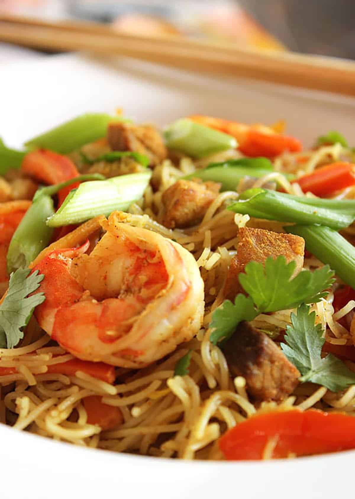 Singapore noodles with shrimp in a white bowl.