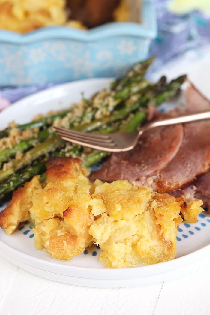 Baked pineapple on a white plate with ham and asparagus.