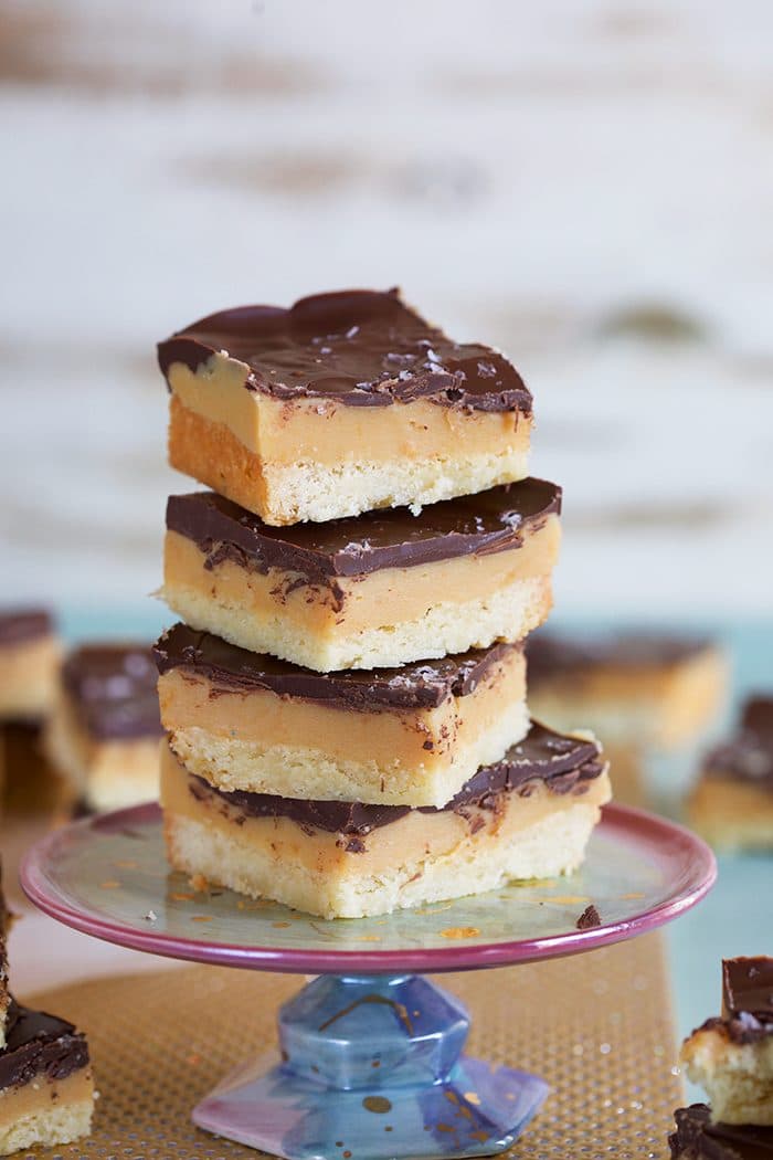Stack of 4 Millionaire Shortbread Bars on a cupcake stand.