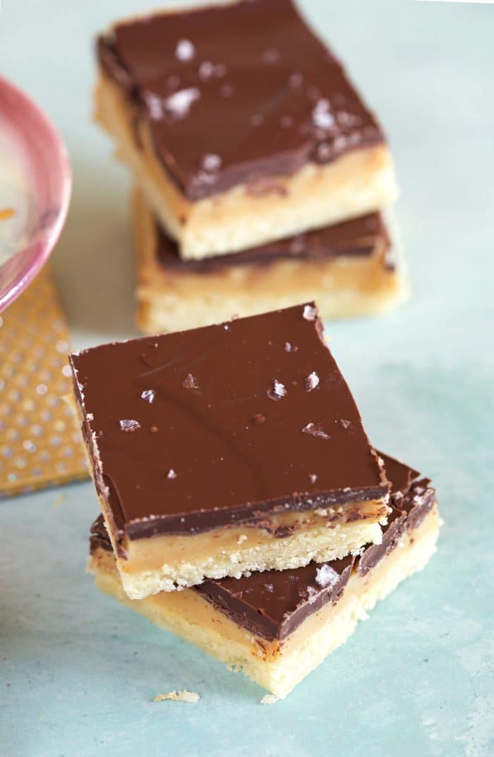 Millionaire Shortbread Bars stacked on a blue background.