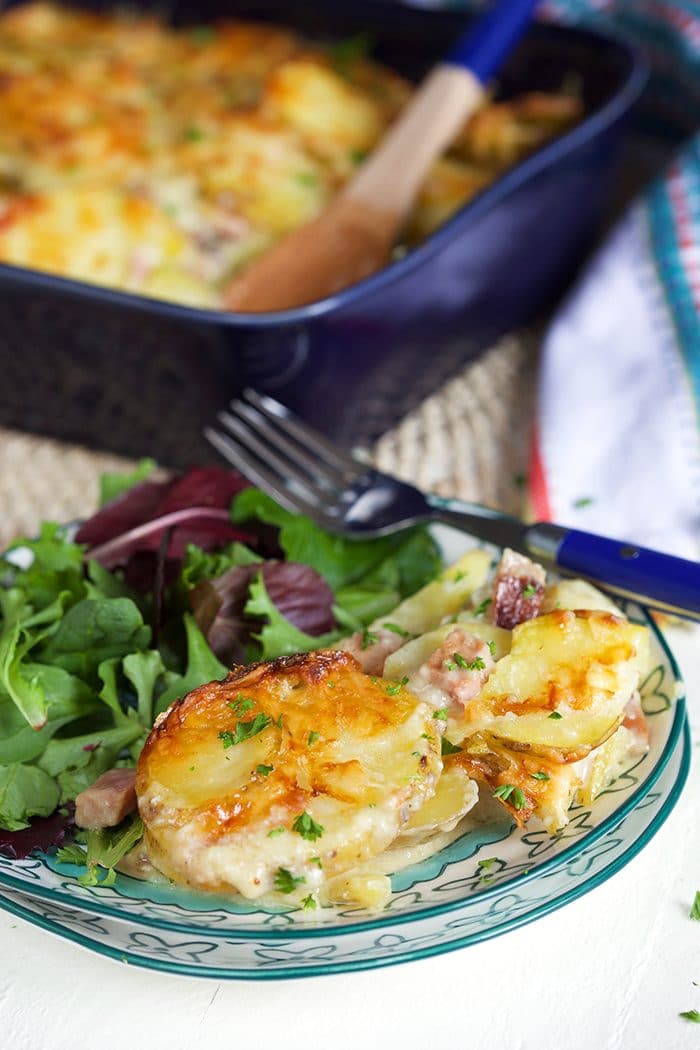 Easy Scalloped Potatoes with ham on a blue and white plate with a green salad.