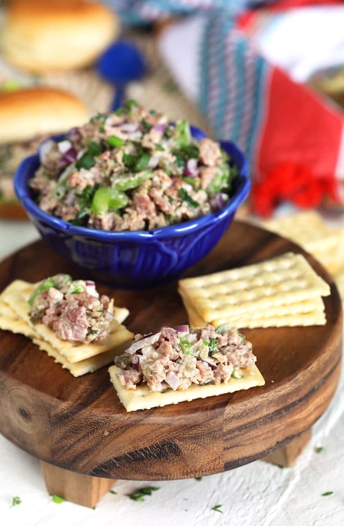 Ham salad on a Town cracker with a bowl of ham salad in a blue bowl.