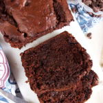 Chocolate banana bread on a marble board with two slices stacked.