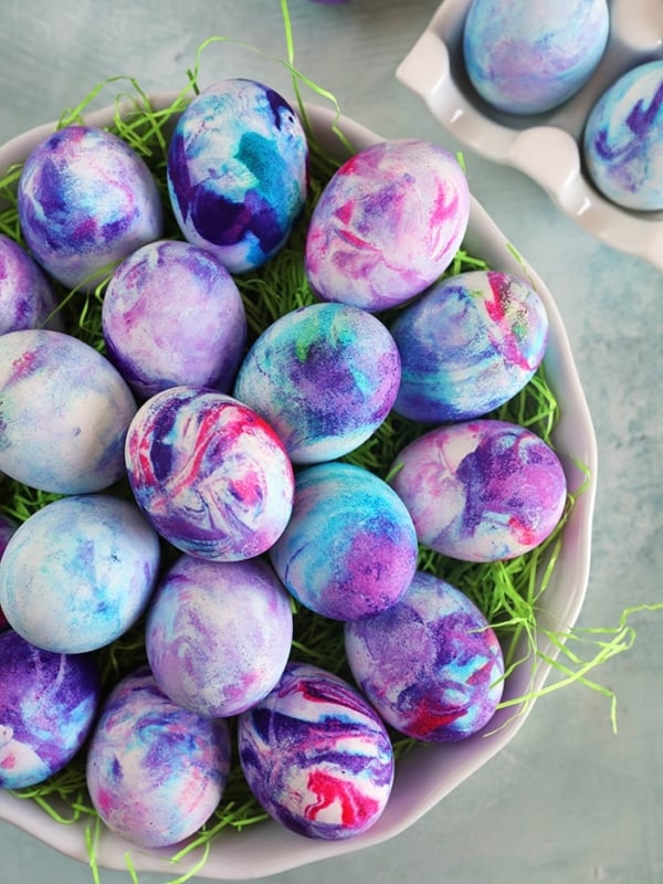 Overhead shot of Whipped Cream Dyed Easter Eggs in a round plate with green easter grass.