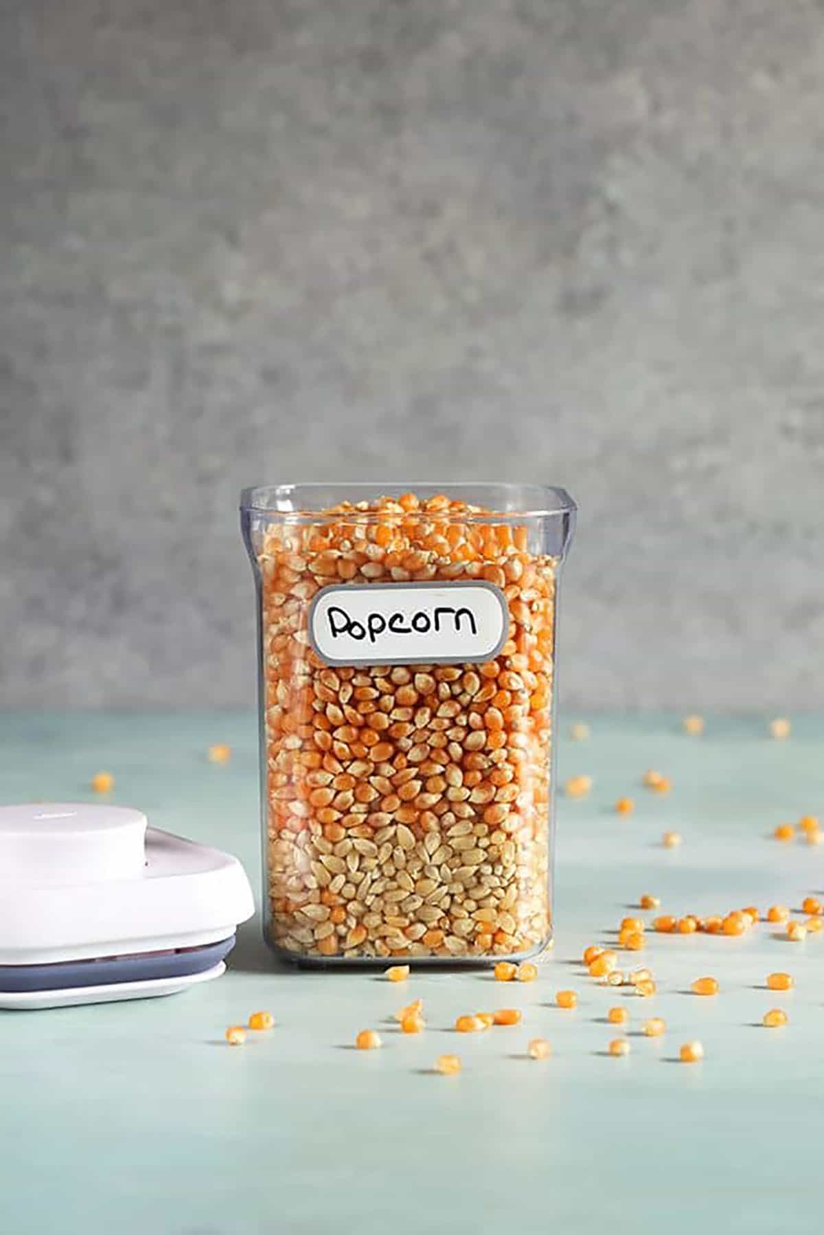 Popcorn kernels in a clear canister with a white lid.