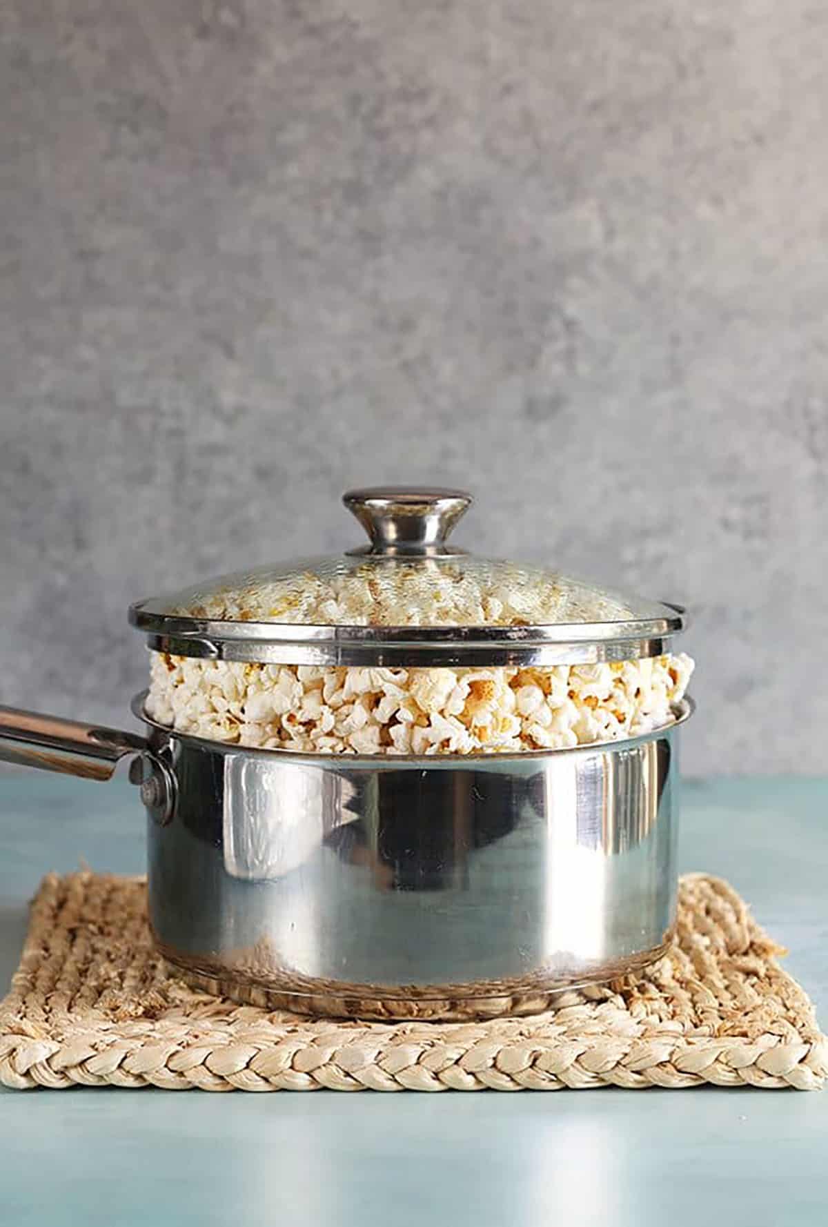 Stovetop popcorn in a stainless steel pot with a glass lid.