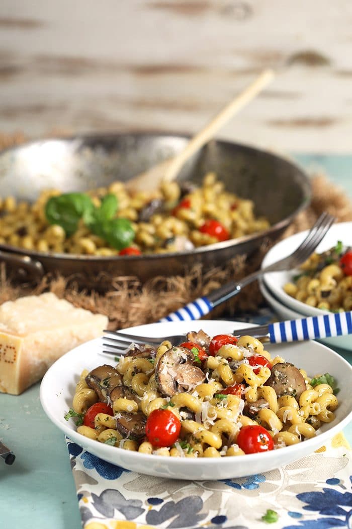 Pesto Cavatappi being served from a skillet into a white bowl.