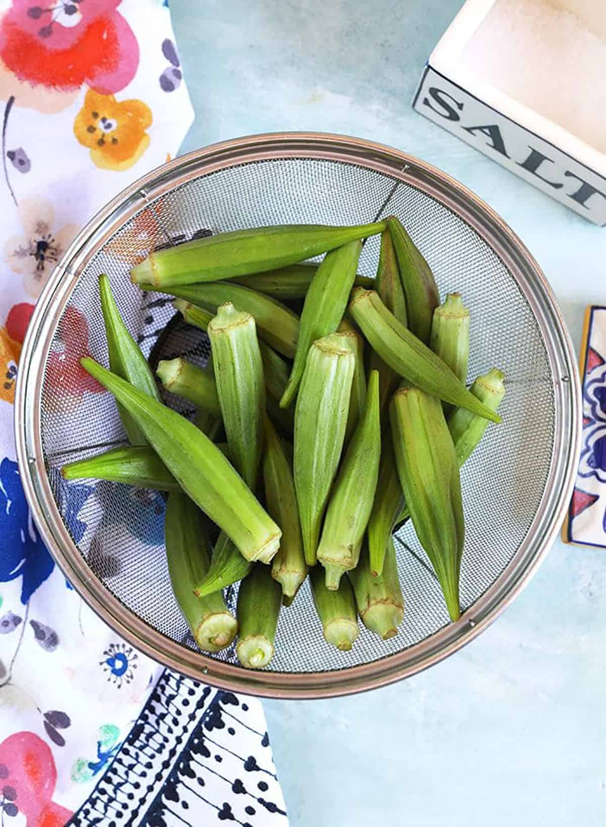 Okra in a strainer with salt.